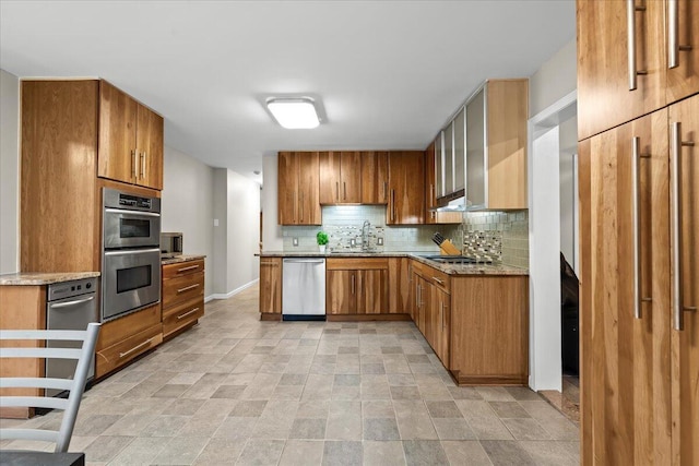 2128 Somerset Rd, Bloomfield Hills, MI 48302 - kitchen featuring stainless steel appliances, a sink, backsplash, brown cabinets, and stone finish flooring