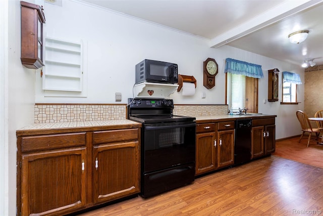 2650 Devonshire, Leonard, MI 48367 - kitchen featuring black appliances, tile countertops, light wood-style floors, tasteful backsplash, and beamed ceiling