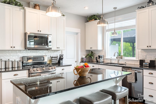 12150 Apple Cart Ln, Lowell, MI 49331 - kitchen with stainless steel appliances, a kitchen breakfast bar, a sink, white cabinetry, and recessed lighting