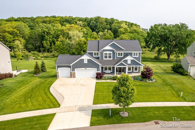 12150 Apple Cart Ln, Lowell, MI 49331 - view of front facade featuring concrete driveway, an attached garage, a front yard, covered porch, and stone siding