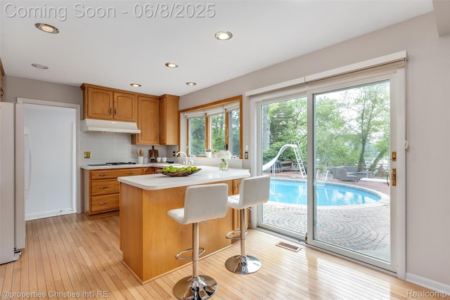 3379 Wormer Dr, Waterford, MI 48329 - kitchen with freestanding refrigerator, light countertops, under cabinet range hood, gas cooktop, and a peninsula
