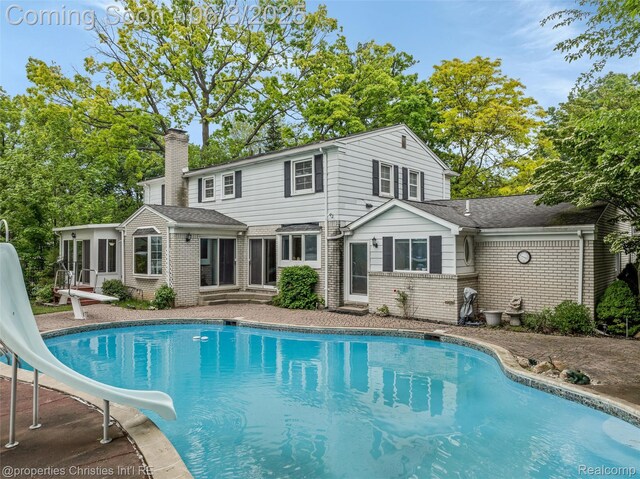 3379 Wormer Dr, Waterford, MI 48329 - rear view of house featuring brick siding, a sunroom, a chimney, and an outdoor pool