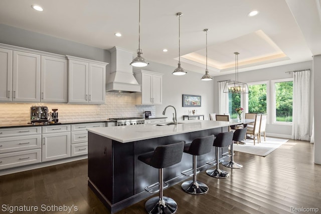 1641 Traceky, Rochester Hills, MI 48306 - kitchen featuring premium range hood, backsplash, a kitchen breakfast bar, a tray ceiling, and dark wood-type flooring