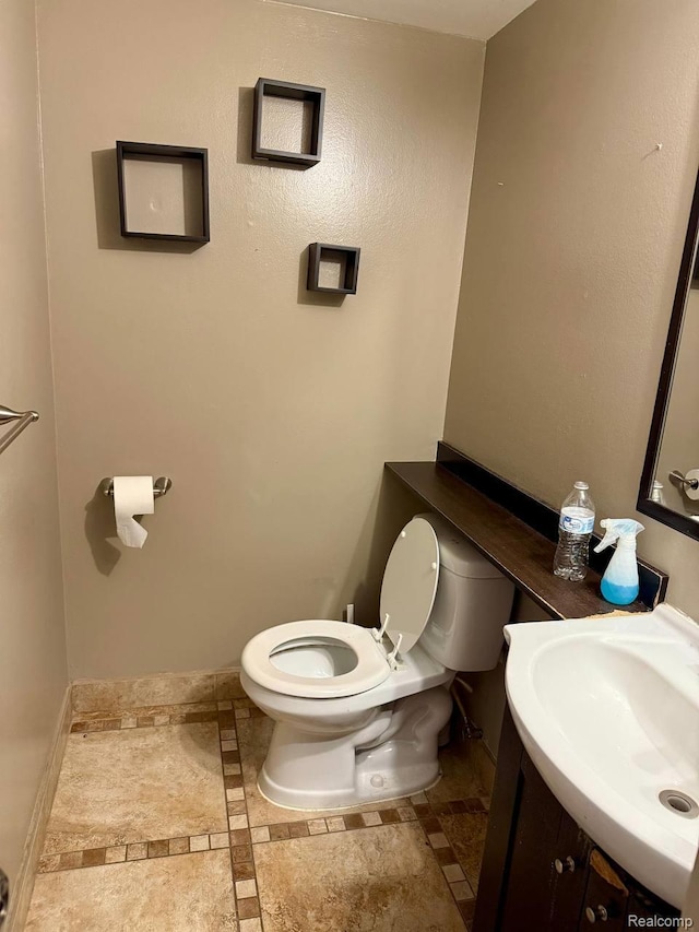38132 Jamestown Dr, Sterling Heights, MI 48312 - bathroom with vanity, toilet, inlaid floor details, and baseboards