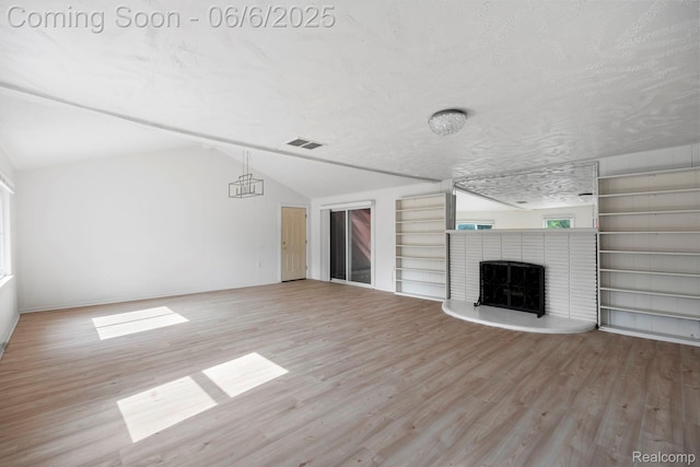 23808 Beierman Ave, Warren, MI 48091 - unfurnished living room featuring vaulted ceiling, wood finished floors, built in shelves, a fireplace, and a textured ceiling