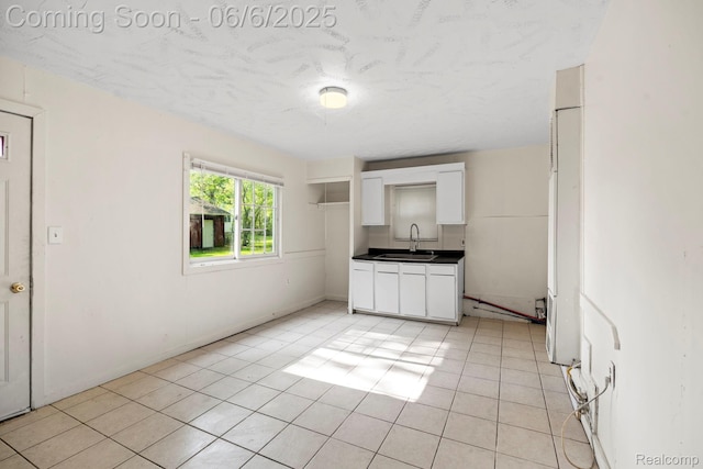23808 Beierman Ave, Warren, MI 48091 - kitchen with a sink, dark countertops, white cabinetry, light tile patterned floors, and baseboards