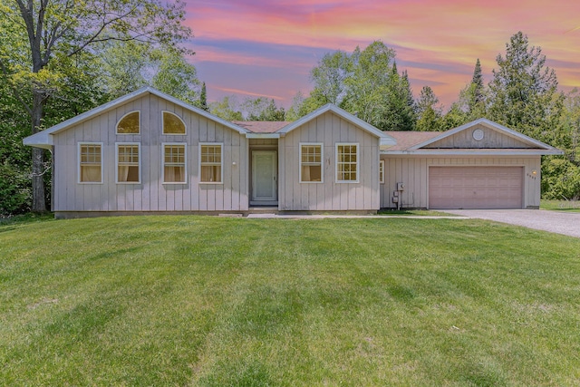 6997 W Woodlea Rd, Oscoda, MI 48750 - view of front of property featuring driveway, an attached garage, a yard, and board and batten siding