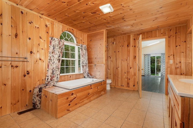 6997 W Woodlea Rd, Oscoda, MI 48750 - bathroom featuring a garden tub, vanity, wood walls, plenty of natural light, and toilet