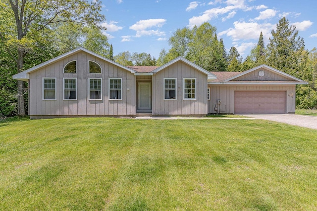 6997 W Woodlea Rd, Oscoda, MI 48750 - view of front facade featuring driveway, a garage, and a front lawn
