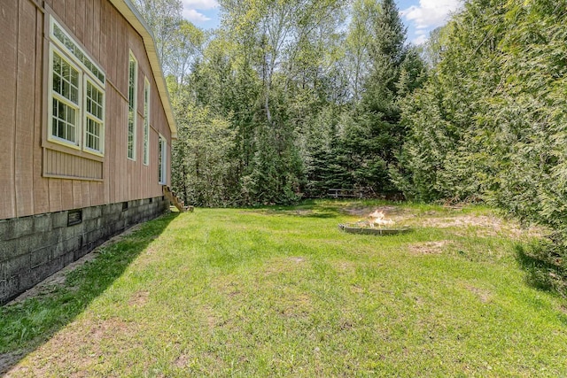 6997 W Woodlea Rd, Oscoda, MI 48750 - view of grassy yard with a fire pit