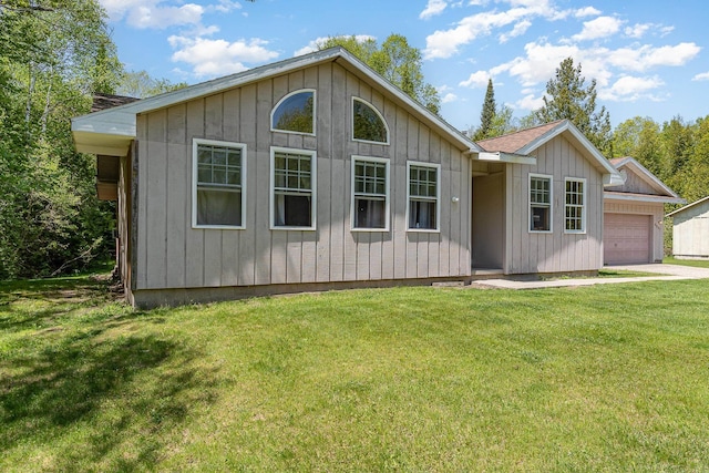 6997 W Woodlea Rd, Oscoda, MI 48750 - view of front of house featuring an attached garage, a front lawn, board and batten siding, and concrete driveway