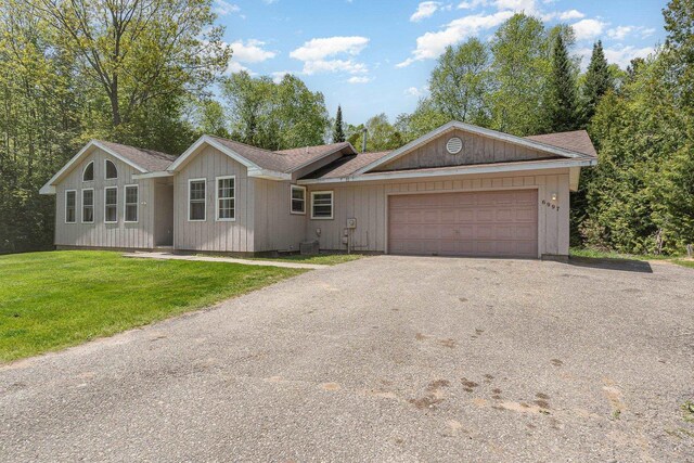 6997 W Woodlea Rd, Oscoda, MI 48750 - ranch-style home with asphalt driveway, an attached garage, and a front yard