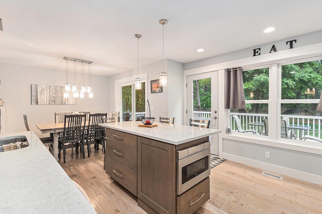 1518 White Pine Ct, Twin Lake, MI 49457 - kitchen with light wood finished floors, light countertops, dark brown cabinets, plenty of natural light, and recessed lighting