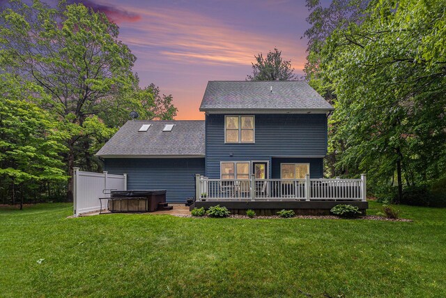 1518 White Pine Ct, Twin Lake, MI 49457 - back of house at dusk featuring a hot tub, roof with shingles, a wooden deck, and a lawn
