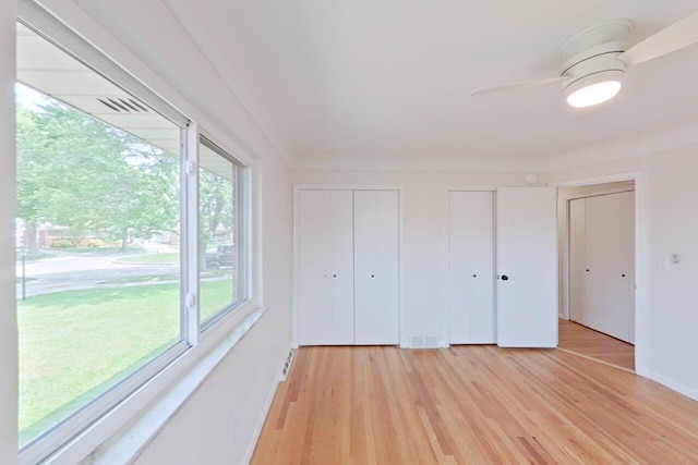 2113 12th St, Wyandotte, MI 48192 - unfurnished bedroom with two closets, light wood-style floors, a ceiling fan, and baseboards