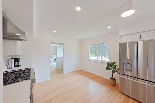 2113 12th St, Wyandotte, MI 48192 - kitchen with appliances with stainless steel finishes, ventilation hood, light wood-style flooring, white cabinetry, and baseboards