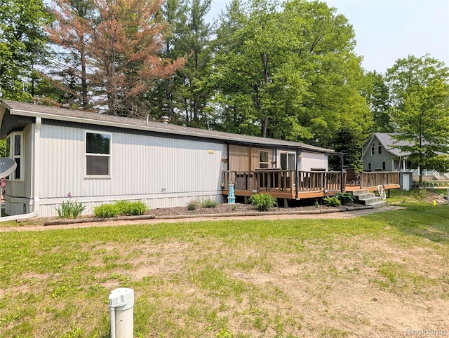 3730 Pinelands Rd, Gladwin, MI 48624 - view of front of property featuring a deck, a front lawn, a shingled roof, and view of scattered trees