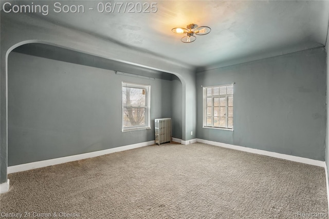15915 Vaughan St, Detroit, MI 48223 - empty room featuring radiator heating unit, arched walkways, plenty of natural light, and carpet floors