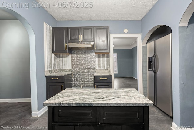 15915 Vaughan St, Detroit, MI 48223 - kitchen featuring stainless steel fridge, decorative backsplash, under cabinet range hood, baseboards, and arched walkways
