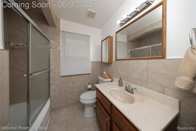 11322 Leverne, Redford, MI 48239 - bathroom with tile walls, vanity, tile patterned flooring, toilet, and bath / shower combo with glass door