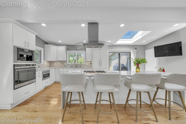 30239 Hickory Ln, Franklin, MI 48025 - kitchen featuring stainless steel appliances, a skylight, island exhaust hood, white cabinets, and light countertops
