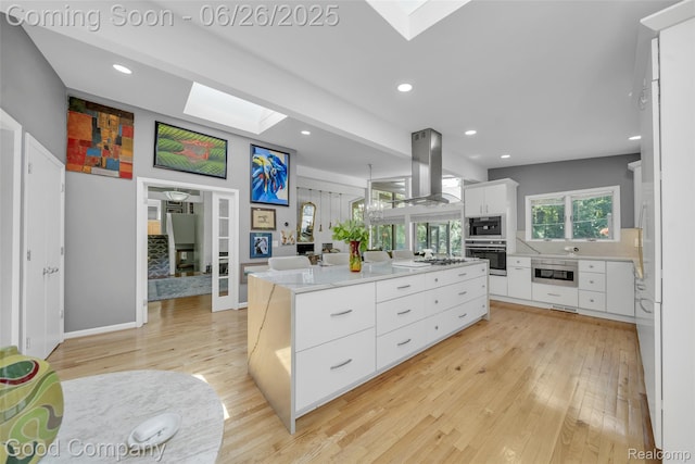 30239 Hickory Ln, Franklin, MI 48025 - kitchen with a skylight, stainless steel oven, island exhaust hood, light wood finished floors, and a center island