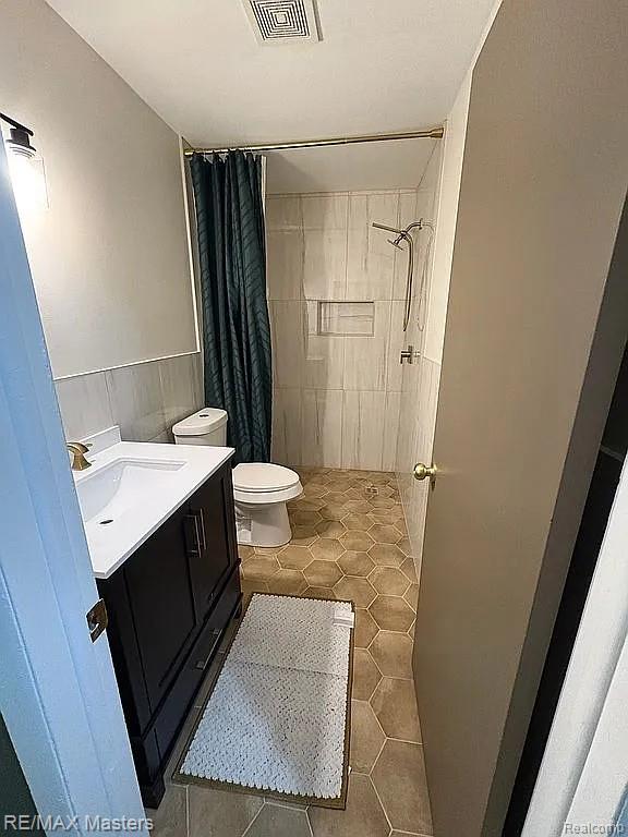 43242 Barchester Rd, Canton, MI 48187 - bathroom featuring tile patterned flooring, vanity, a shower with shower curtain, toilet, and tile walls