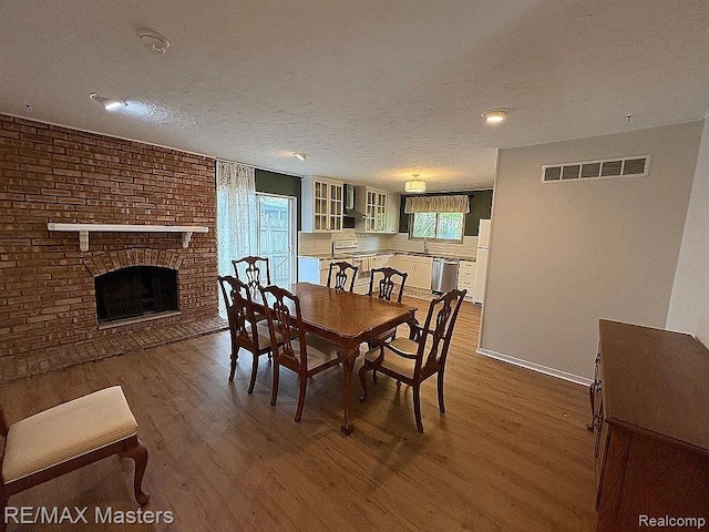 43242 Barchester Rd, Canton, MI 48187 - dining room with wood finished floors, plenty of natural light, a brick fireplace, a textured ceiling, and baseboards