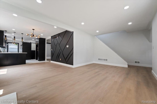 17169 Griggs St, Detroit, MI 48221 - unfurnished living room featuring light wood-style flooring, a barn door, baseboards, and recessed lighting