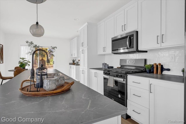 2819 16th St, Detroit, MI 48216 - kitchen featuring stainless steel appliances, backsplash, white cabinetry, and pendant lighting