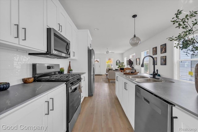 2819 16th St, Detroit, MI 48216 - kitchen featuring stainless steel appliances, white cabinetry, open floor plan, light wood finished floors, and pendant lighting