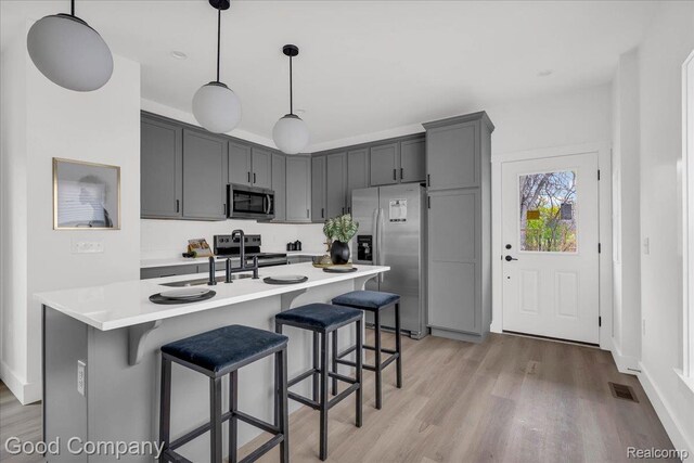 2827 16th St, Detroit, MI 48216 - kitchen featuring appliances with stainless steel finishes, light wood-style flooring, light countertops, and a breakfast bar area