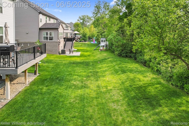 861 N Mill St, South Lyon, MI 48178 - view of green lawn featuring a deck, a playground, and cooling unit