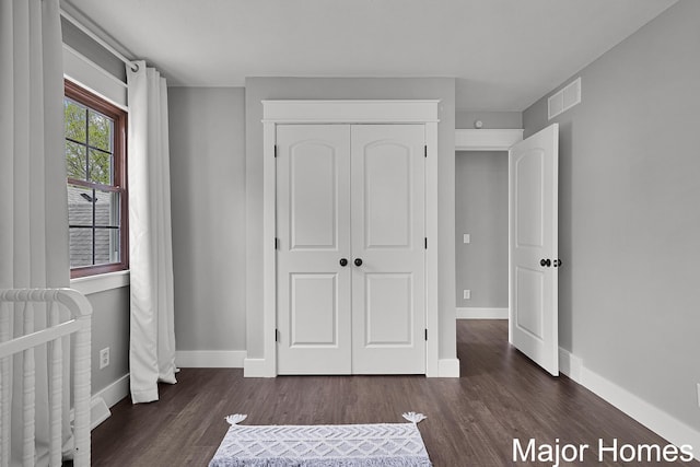 7125 Brooklyn Ave SE, Grand Rapids, MI 49508 - unfurnished bedroom with dark wood-type flooring, a closet, and baseboards