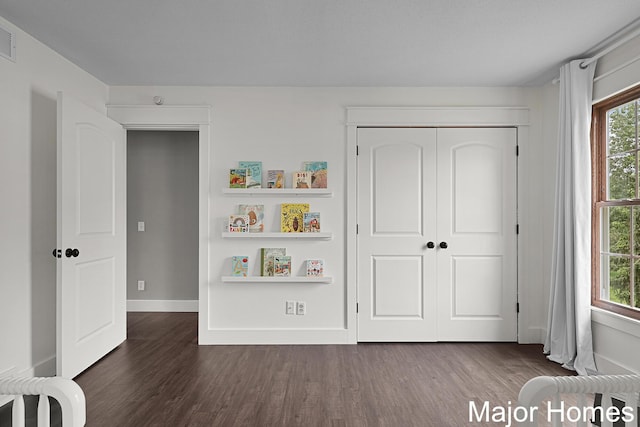 7125 Brooklyn Ave SE, Grand Rapids, MI 49508 - unfurnished bedroom featuring dark wood-style floors, a closet, and baseboards