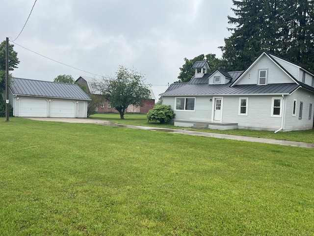855 E Hansen Rd, Scottville, MI 49454 - view of front of home with a standing seam roof, a garage, metal roof, a front yard, and an outdoor structure