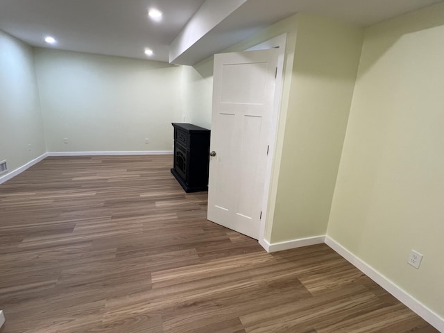 855 E Hansen Rd, Scottville, MI 49454 - finished basement featuring a wood stove, wood finished floors, baseboards, and recessed lighting