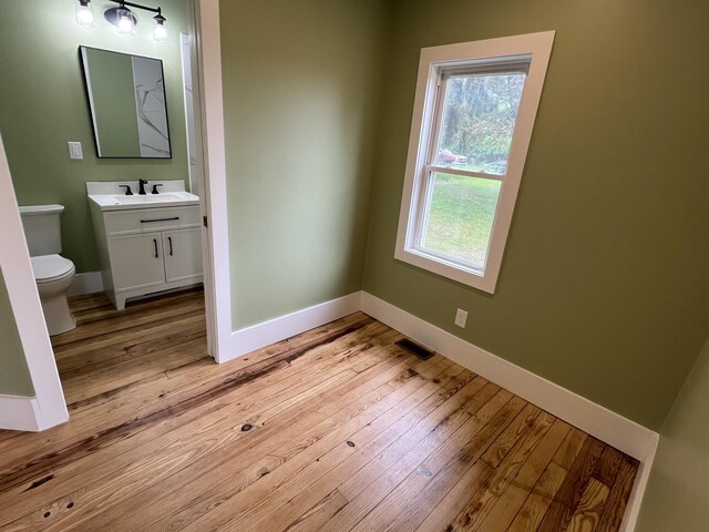 855 E Hansen Rd, Scottville, MI 49454 - bathroom with toilet, vanity, wood finished floors, and plenty of natural light