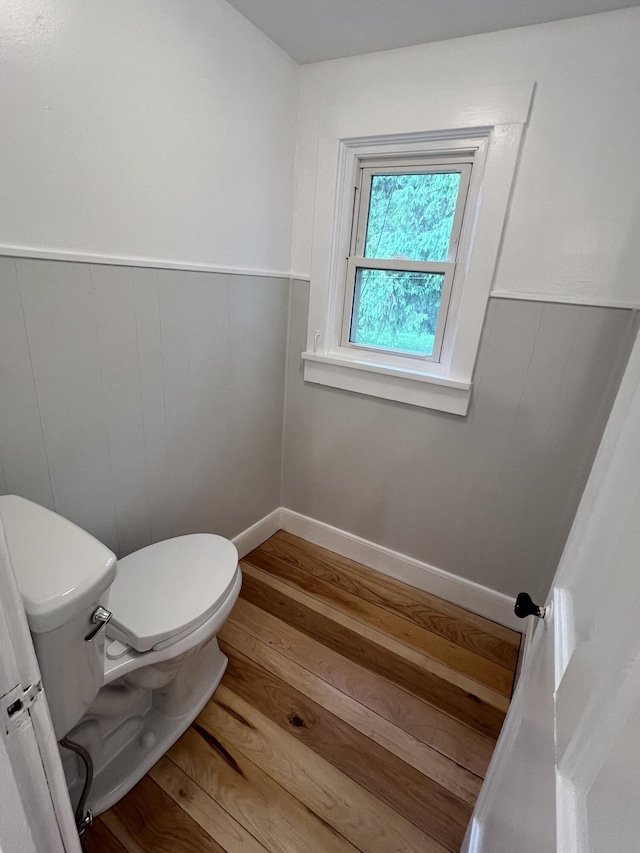 855 E Hansen Rd, Scottville, MI 49454 - bathroom featuring wood finished floors, toilet, and a wainscoted wall