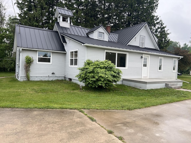 855 E Hansen Rd, Scottville, MI 49454 - view of front of house with a front lawn, a chimney, and metal roof