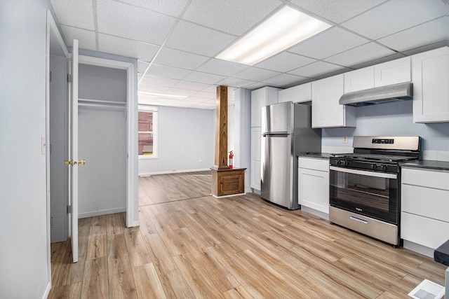 707 Maple St, Big Rapids, MI 49307 - kitchen with stainless steel appliances, under cabinet range hood, a paneled ceiling, dark countertops, and white cabinets