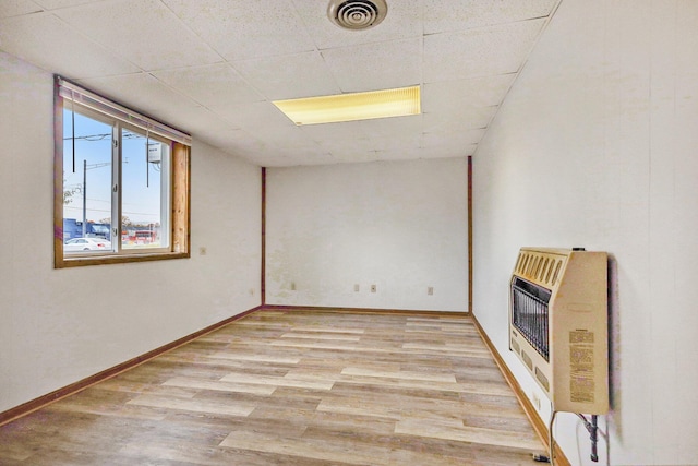 707 Maple St, Big Rapids, MI 49307 - empty room featuring heating unit, light wood-style floors, a paneled ceiling, and baseboards