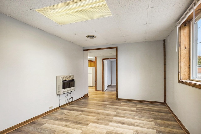 707 Maple St, Big Rapids, MI 49307 - unfurnished living room featuring heating unit, a paneled ceiling, baseboards, and light wood-style floors