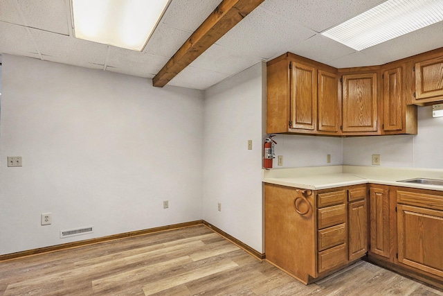 707 Maple St, Big Rapids, MI 49307 - kitchen featuring light wood finished floors, brown cabinets, light countertops, baseboards, and a paneled ceiling