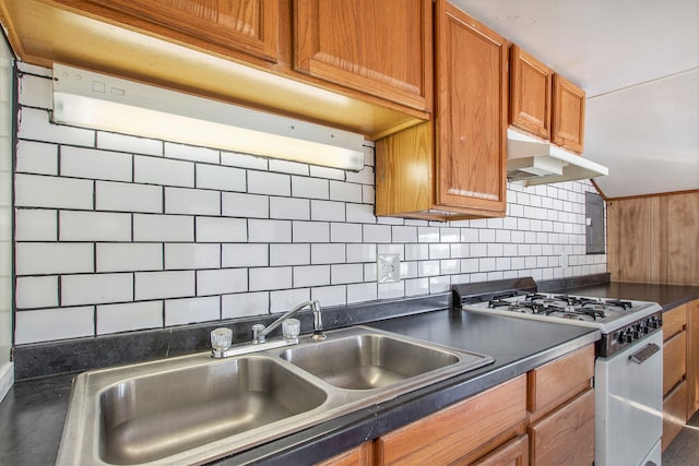 707 Maple St, Big Rapids, MI 49307 - kitchen featuring white gas stove, under cabinet range hood, a sink, dark countertops, and brown cabinets