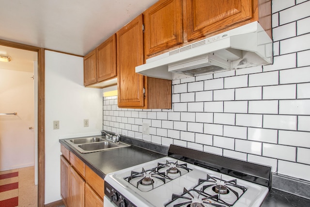 707 Maple St, Big Rapids, MI 49307 - kitchen with under cabinet range hood, range with gas cooktop, tasteful backsplash, a sink, and dark countertops