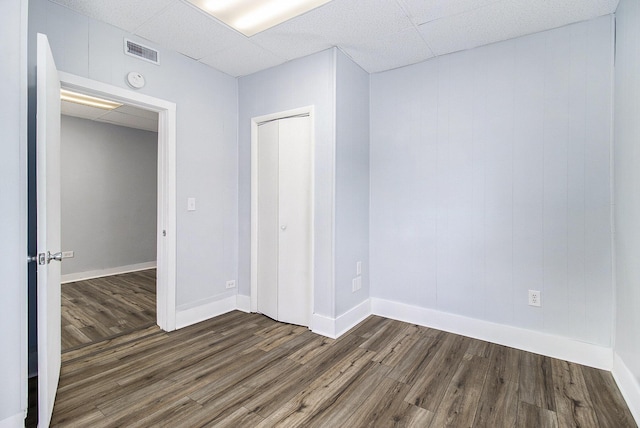 707 Maple St, Big Rapids, MI 49307 - unfurnished bedroom featuring dark wood-style floors, baseboards, a closet, and a drop ceiling