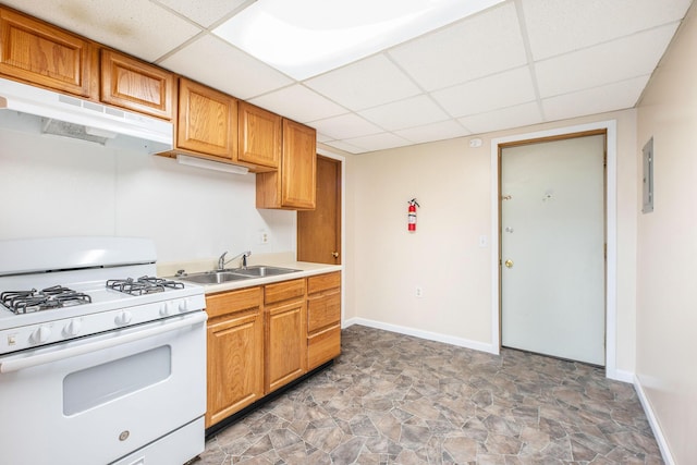 707 Maple St, Big Rapids, MI 49307 - kitchen with white range with gas stovetop, under cabinet range hood, a sink, a drop ceiling, and stone finish floors