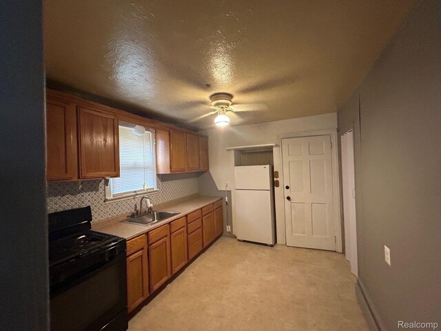 18821 Dalby, Redford, MI 48240 - kitchen featuring black range with gas stovetop, freestanding refrigerator, a sink, tasteful backsplash, and brown cabinetry