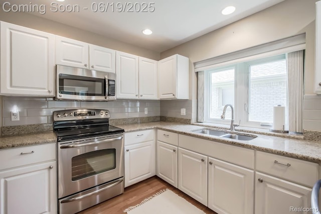 43221 Pointe Dr Unit 57, Clinton Township, MI 48038 - kitchen featuring appliances with stainless steel finishes, white cabinets, tasteful backsplash, light wood-type flooring, and recessed lighting